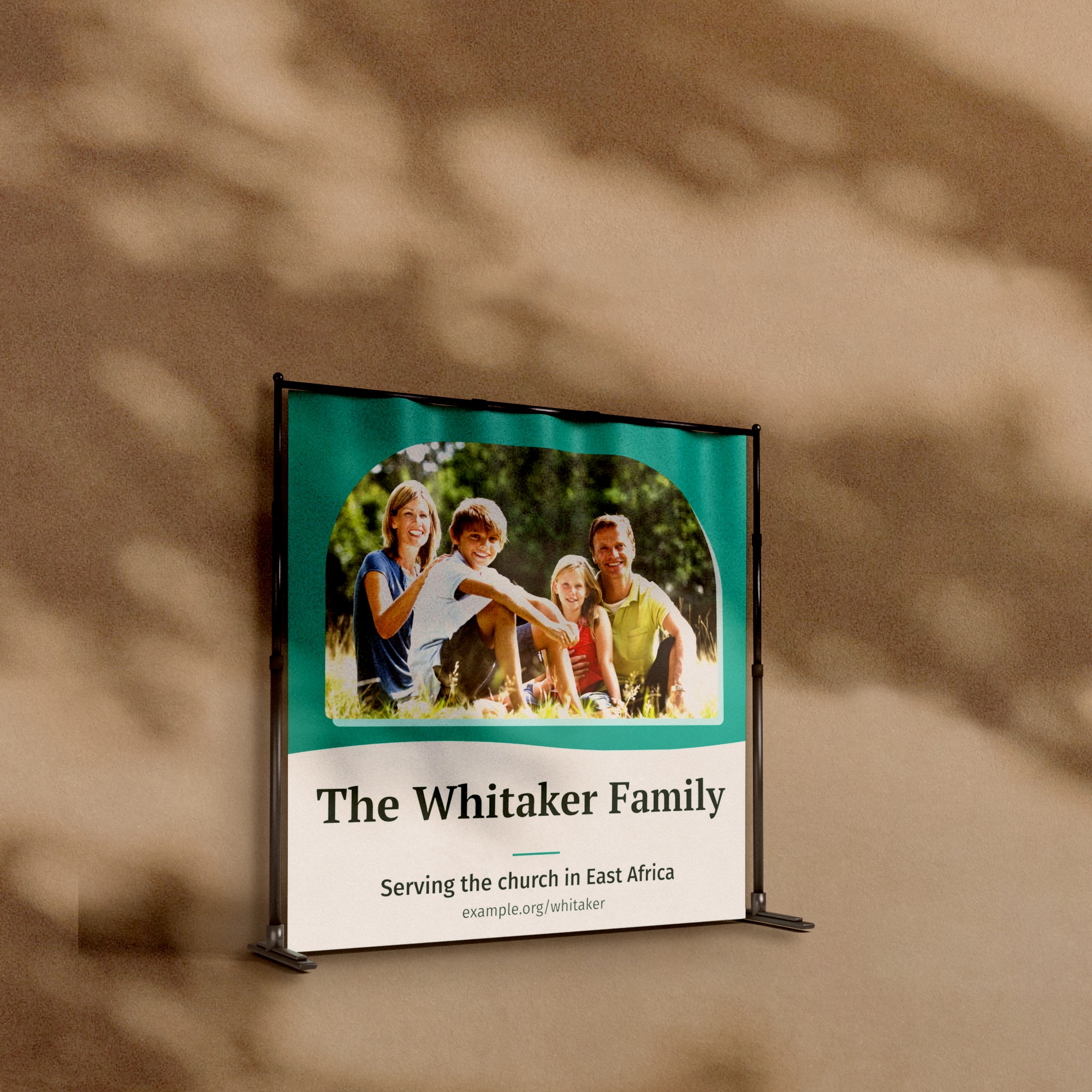 A telescopic backdrop stand with a 95 by 96 inch printed vinyl backdrop of a family photograph and the words The Whitaker Family, against a warm plaster wall